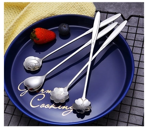 Macro view of four assorted flower-shaped stainless steel spoons on a blue ceramic plate