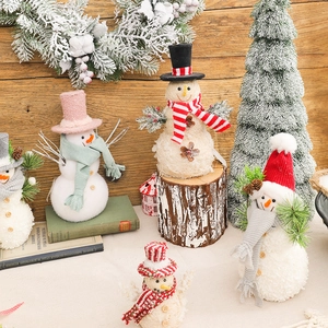 Festive Christmas snowmen figurines with knitted hats and scarves on wooden background