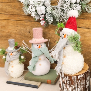 Three plush Christmas snowmen set with knit hats on a warm wooden rustic background