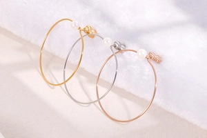 Close-up of gold, silver, and rose gold hoop earrings with pearls and butterfly studs