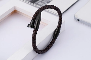 Detailed close-up of a woven black leather cord bracelet with a stainless steel nail clasp