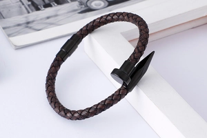 Detailed view of brown braided leather rope bracelet with black nail-shaped metal buckle