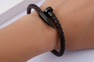 Detail of woven black leather rope bracelet with matte black metal nail head buckle