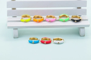 Detail of colorful enamel hoop earrings with zircon stones on a white wooden chair