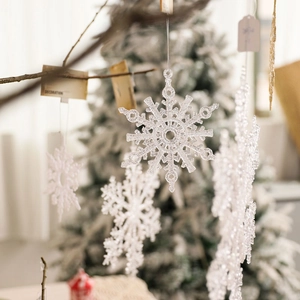 Sparkling transparent snowflake ornament with silver string hanging on a Christmas tree