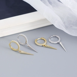 Macro view of gold and silver S925 sterling silver hoop earrings with spike pendants
