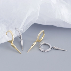 Detailed view of silver and gold spiked hoop earrings with zircon accents on soft background