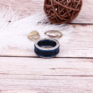 Retro stainless steel punk ring with blue inlay and rivet details on wood background