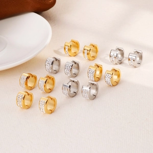 Classic gold and silver huggie earrings with cubic zirconia pave on beige linen