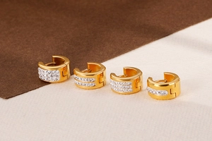 Macro view of gold plated huggie earrings with white cubic zirconia micro-pave settings