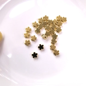 Close-up of small 14K gold filled flower spacer beads scattered on white ceramic plate