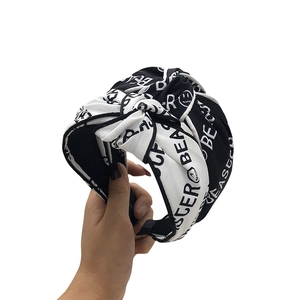Hand holding a knotted fabric headband featuring black and white Beaster letter patterns