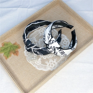 Black and white wide knotted headbands featuring bear and smiley face prints in a tray