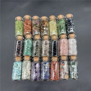 Overhead view of 21 corked glass bottles filled with colorful natural healing crystal chips