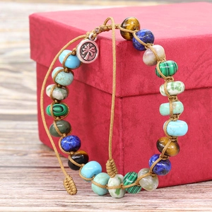 Close-up of woven stone bracelet featuring multi-color beads and palm tree charm