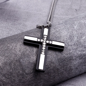 Detail of black and silver cross pendant necklace with sparkling crystal inlay on box chain