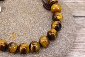 Macro shot of tiger eye beads on woven rope showcasing cat-eye effect and texture