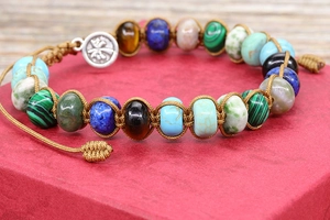 Macro detail of hand-woven bracelet with colorful natural stones and silver tree pendant
