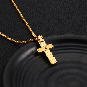 Macro shot of a gold layered cross pendant featuring a centered black gemstone on leather