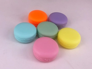 Top view of six colorful macaron-shaped plastic cosmetic containers in pastel colors