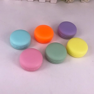 Set of 6 macaron-shaped plastic cream jars in assorted colors on white background