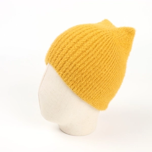 Detail of fluffy yellow knitted beanie with cute fox ears on a white display head