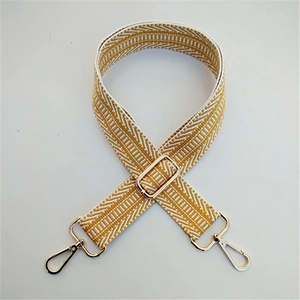 Detail of yellow and beige geometric jacquard strap with polished gold metal swivel hooks
