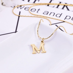 Golden M-letter pendant necklace with sleek snake chain on a minimalist display