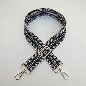Detail of adjustable black and white geometric strap with gold-tone metal hooks