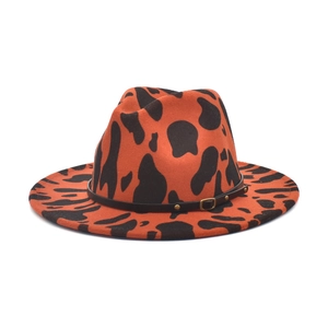 Détail du chapeau fedora motif vache en feutre orange avec ceinture en cuir à rivets