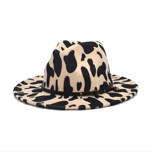Détail d'un chapeau fedora à motif vache avec bande en cuir et boucle dorée