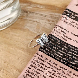Detailed view of an S925 sterling silver butterfly open ring on a soft pink accessory