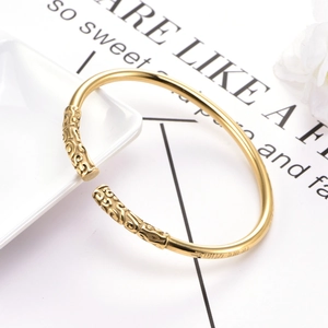 Golden open cuff bracelet with vintage auspicious cloud patterns on white ceramic plate