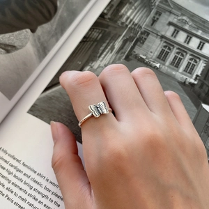 Detail of a 925 silver butterfly ring on model's finger with a magazine backdrop