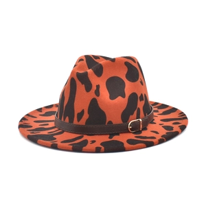 Detail of orange cow print wool fedora featuring a brown leather band and gold buckle