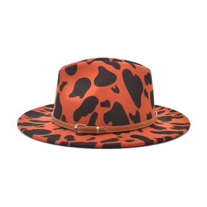 Detail of orange fedora with cow print, brown leather band and gold metal buckle