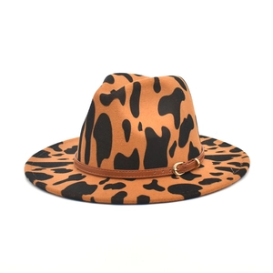 Close-up of wide brim fedora with cow print pattern and brown leather buckle belt