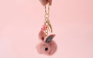 Detailed view of pink faux fur bunny keychain with soft felt ears and golden metal ring