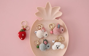 Detail of cute cartoon wool felt keychains with rabbits and strawberry on a pink plate
