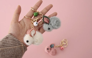 Close-up of plush rabbit keychains in grey and white with metal bells and chains