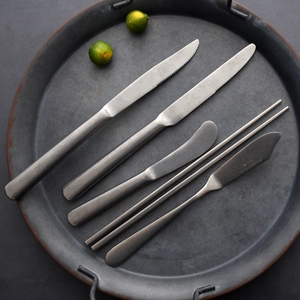 Classic retro matte grey metal cutlery set with steak knives and chopsticks on a tray