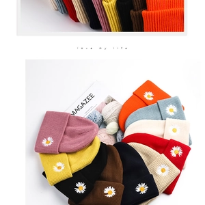 Top view of colorful knitted daisy beanies arranged in a circle for winter warmth