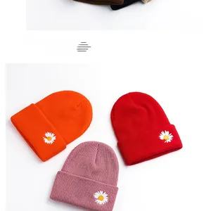 Detailed embroidery of daisies on ribbed knit beanies in orange, red, and pink colors