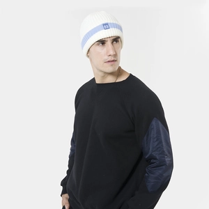 Détail du bonnet blanc avec broderie 89 et du sweat-shirt noir à empiècements aux coudes