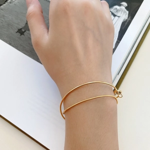 Detail of minimalist gold double-layer bracelet with rigid ring and snake chain on wrist