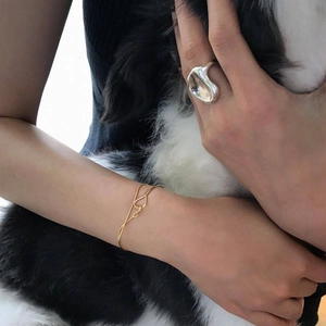 Close-up of a silver irregular polished ring and gold thin chain bracelet on model wrist