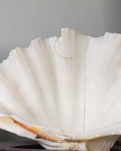 Close-up of minimalist gold 925 sterling silver snake chain bracelet on a white shell