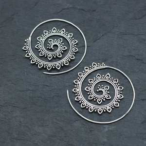 Vintage silver lotus spiral hoop earrings with bohemian tribal textures on stone background