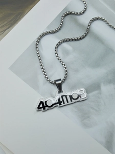 Gros plan du collier argenté avec pendentif lettrage creux 404MOB en acier titane