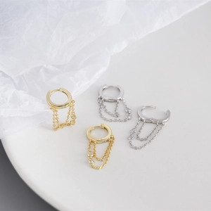 Detail of silver and gold geometric tassel earrings with diamonds on a ceramic dish